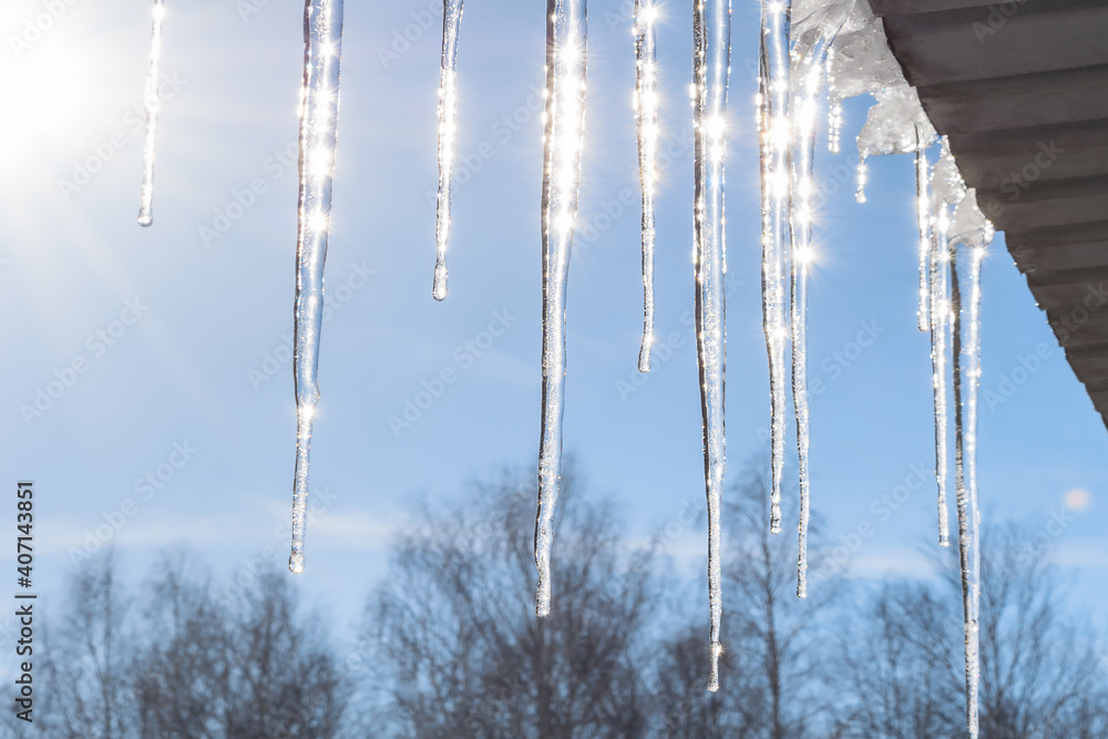 Icicles against a blue sky in severe frost. Long shiny icicles hang from the roof in the sunlight. Photo taken in the Urals, Russia. Bright photomurals of nature. beauty is in the details. Icicles against a blue sky in severe frost. Long shiny icicles hang from the roof in the sunlight. Photo taken in the Urals, Russia. Bright photomurals of nature. beauty is in the details.