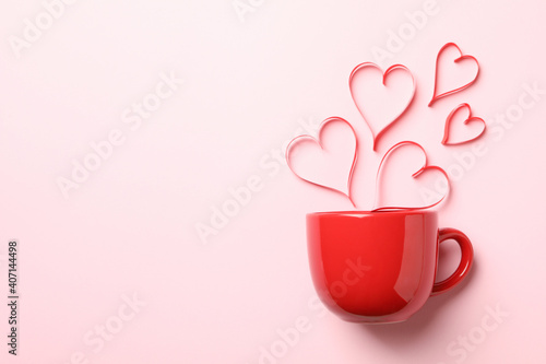 Red cup and decorative hearts on pink background