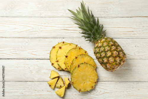 Pineapple and slices on white wooden background