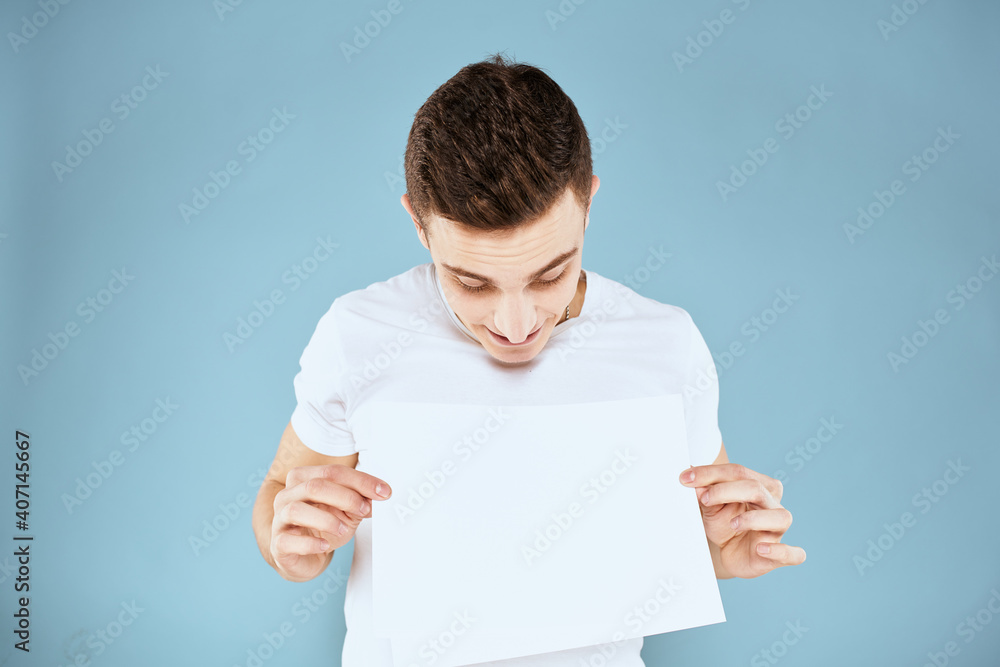 man holding a sheet of paper in his hands white t-shirt cropped view blue background