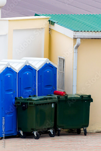A green trash cans on wheels and a portable toilet cabins in blue © rostovdriver