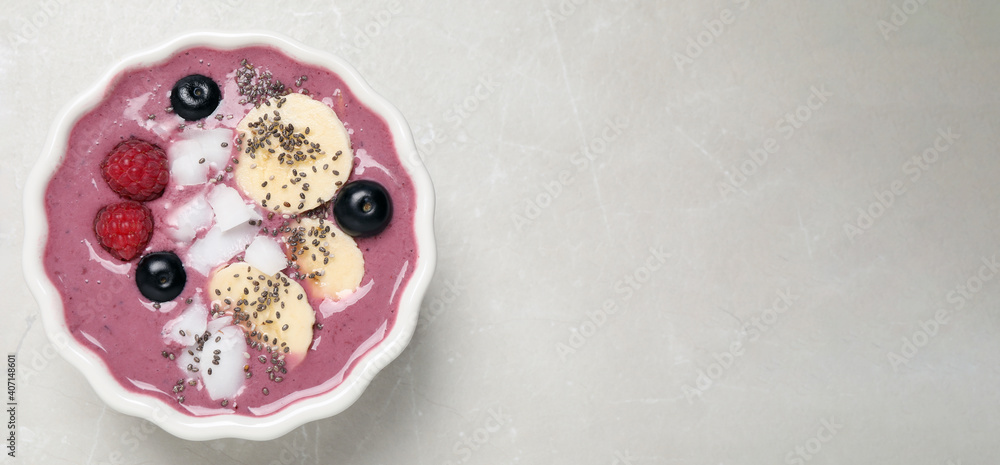 Delicious acai smoothie with fruits and coconut chips in dessert bowl on grey table, top view. Space for text Delicious acai smoothie with fruits and coconut chips in dessert bowl on grey table, top view. Space for text