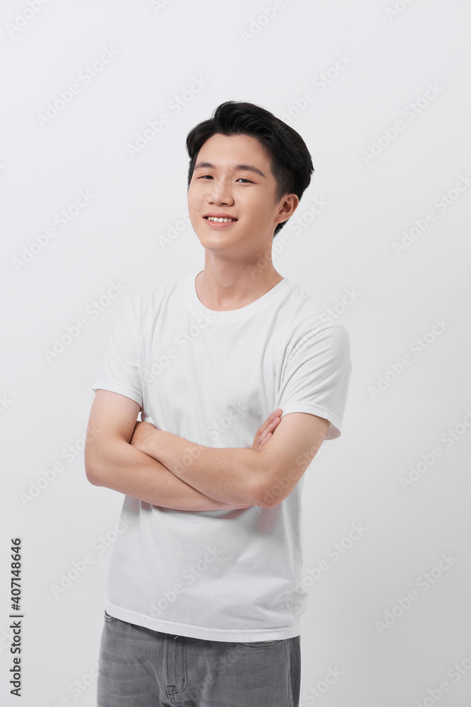 Portrait of smiling handsome man in white t-shirt, standing with crossed arms isolated on gray background Portrait of smiling handsome man in white t-shirt, standing with crossed arms isolated on gray background