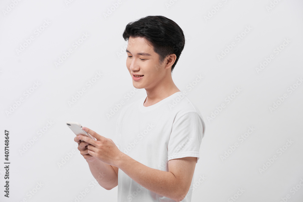 Handsome smiling man in white t-shirt holding smartphone and typing sms. Handsome smiling man in white t-shirt holding smartphone and typing sms.