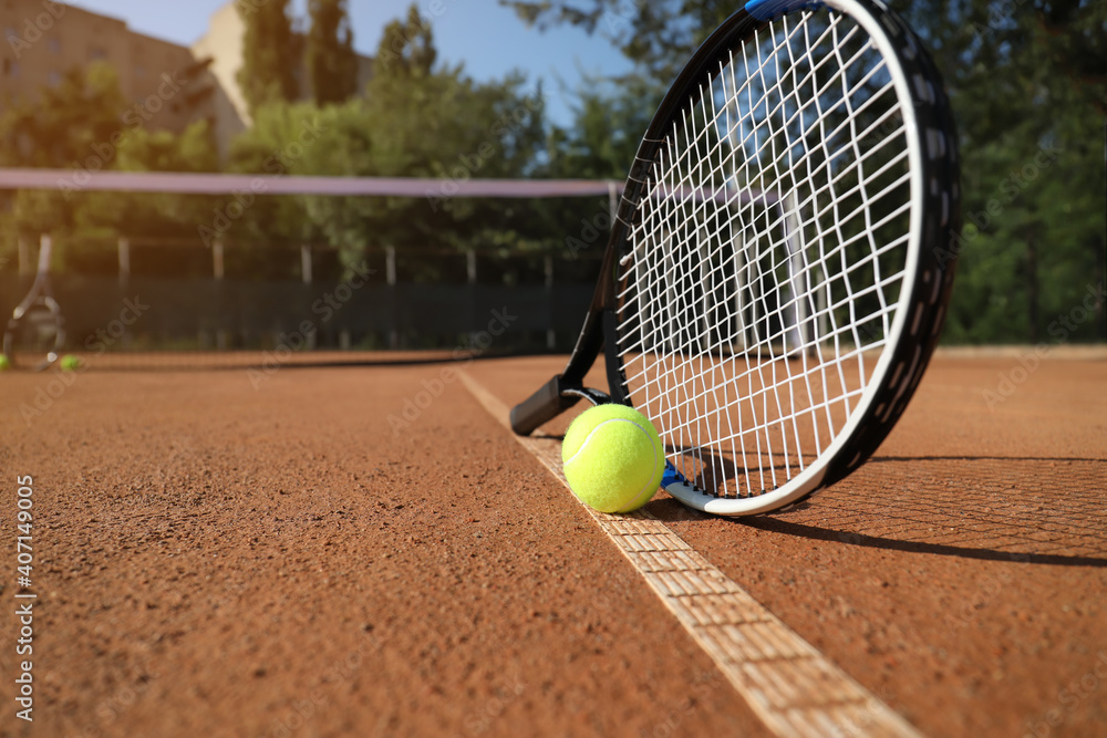 Tennis ball and racket on clay court