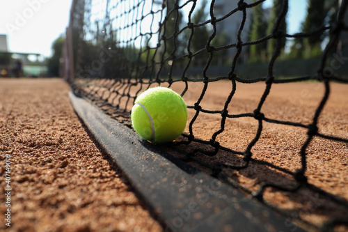 Tennis ball near net on clay court, closeup © New Africa