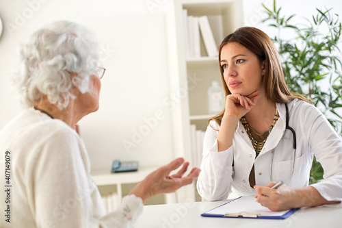 Young atractive doctor listen carefully her senior patient © didesign