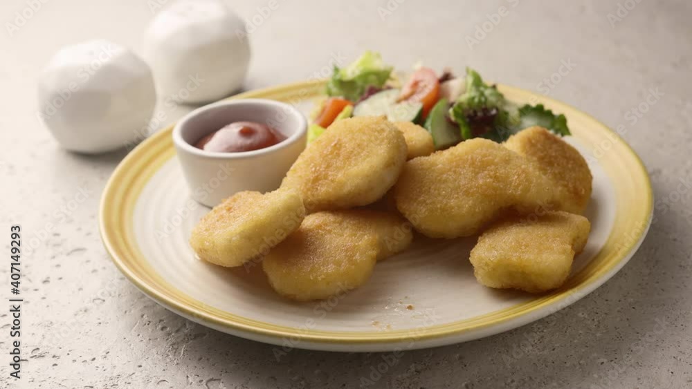 A man picks up a nugget from a plate and dips it in ketchup A man picks up a nugget from a plate and dips it in ketchup