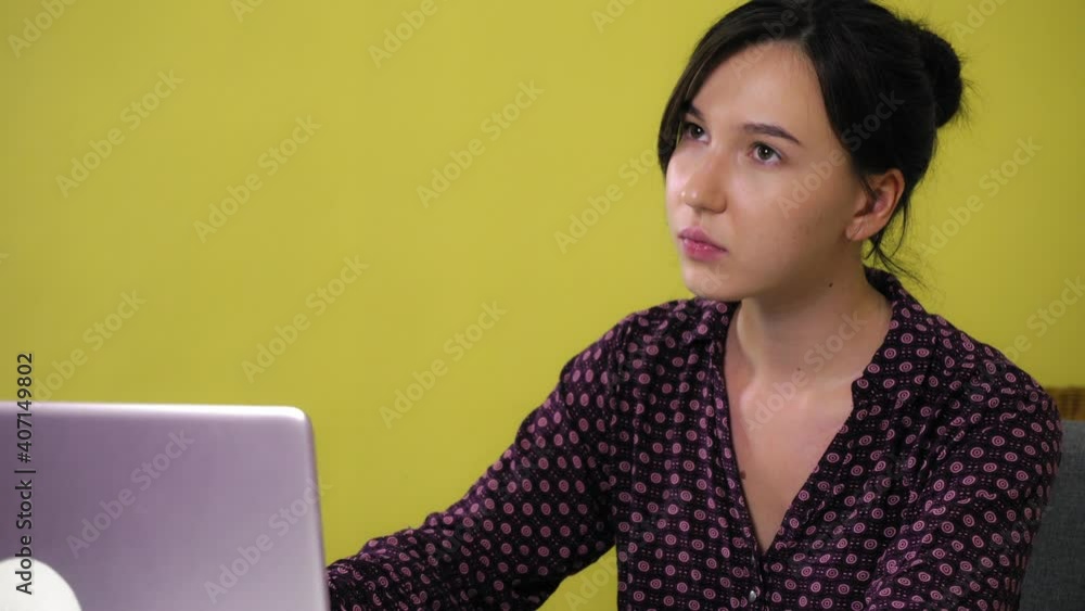 A young mixed race woman sits at home and is engaged online on a laptop, making notes in a notebook. A woman communicates at work or in a distance class. A young mixed race woman sits at home and is engaged online on a laptop, making notes in a notebook. A woman communicates at work or in a distance class.