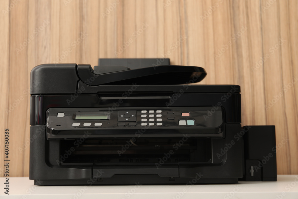 New modern printer on white table against wooden background New modern printer on white table against wooden background