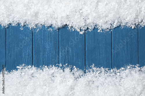 Frame made of snow on blue wooden background  top view with space for text. Christmas time