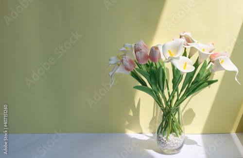 Artificial bouquet in glass vase, pink tulips and white calla lilies