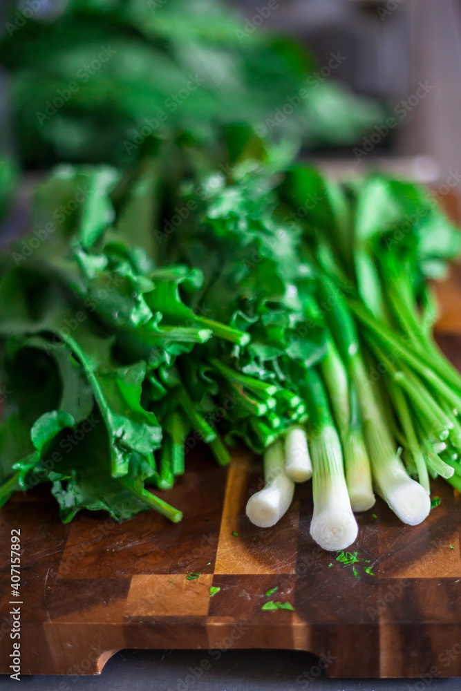 Bunch of green (spring) onion and fresh spinach on a cutting board Bunch of green (spring) onion and fresh spinach on a cutting board