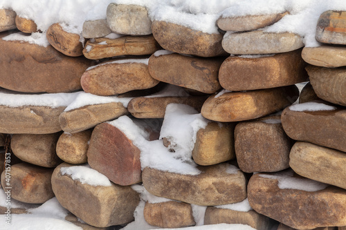 Stacked stones, covered with snow. A wall of stones.