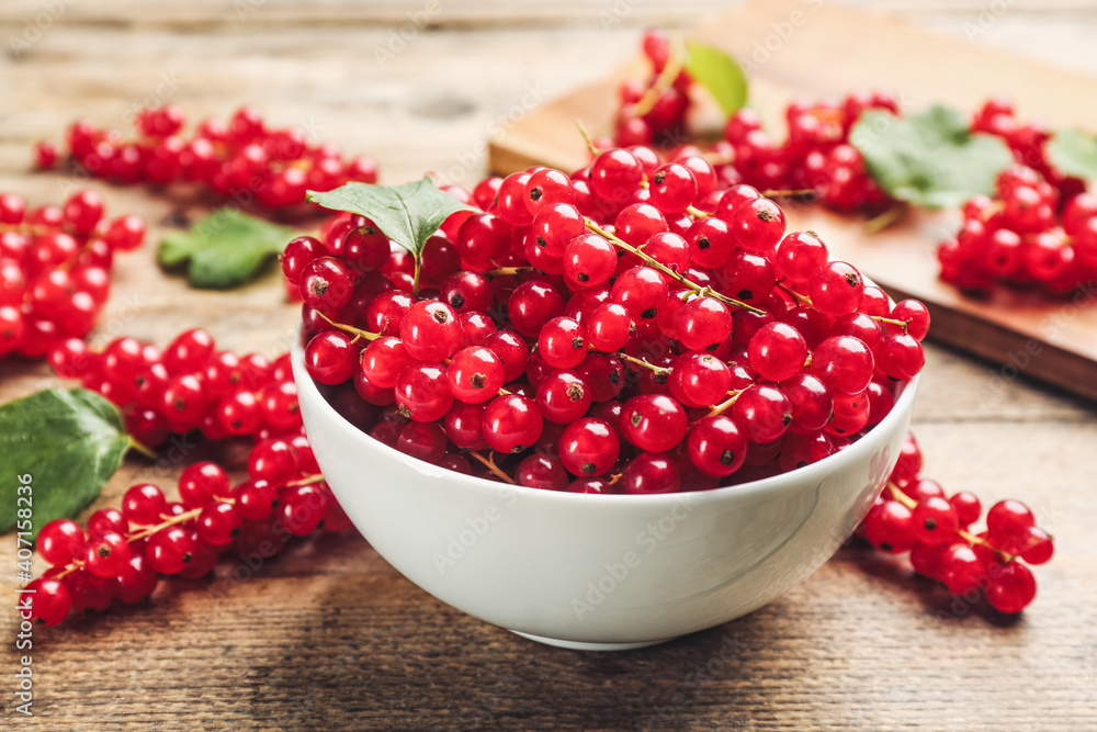 Delicious red currants in bowl on wooden table Delicious red currants in bowl on wooden table
