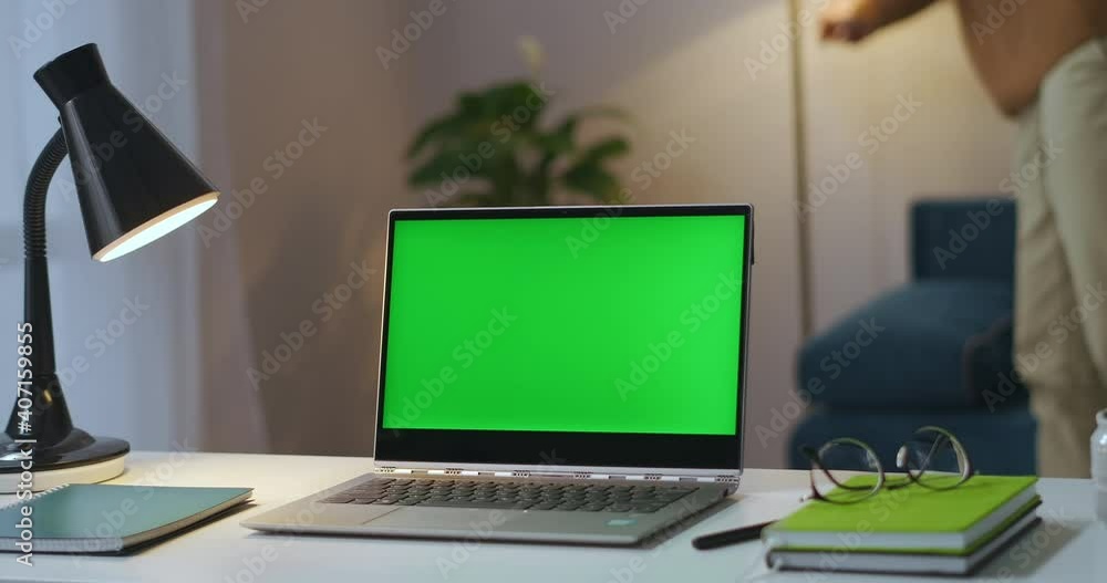 man is turning off floor lamp in flat and closing laptop with chroma key display on table in room, home office of freelancer man is turning off floor lamp in flat and closing laptop with chroma key display on table in room, home office of freelancer