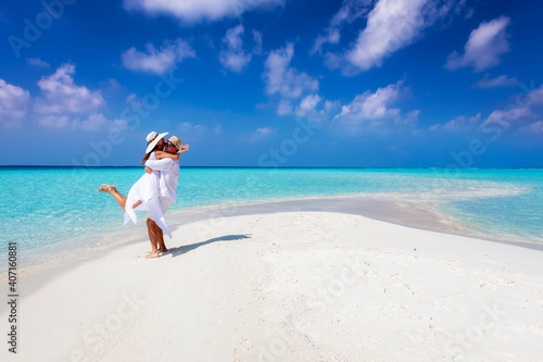 Bild auf Leinwand Happy couple in love is having fun and hugging on a sandbar with white sand and