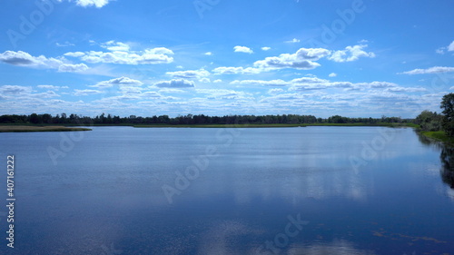 Clouds are reflected in the lake. View of the lake in the distant grass and clouds