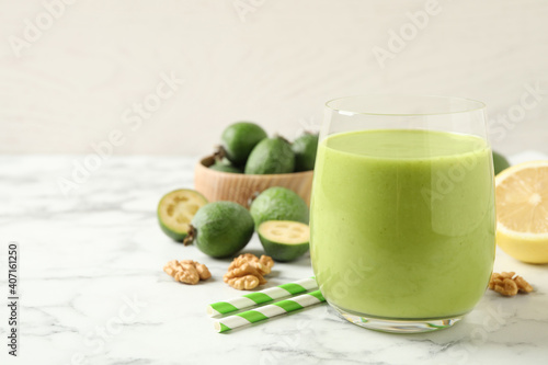 Fresh feijoa smoothie in glass on white marble table, closeup. Space for text