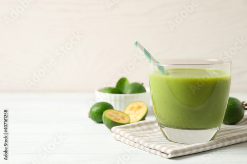 Fresh feijoa smoothie in glass on white wooden table, closeup. Space for text