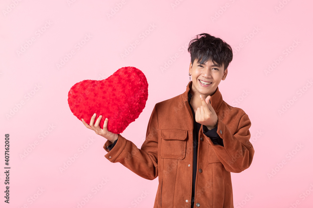 Valentine's day concept, Asian a man handsome young holding a red heart shaped pillow in love isolated on pink blank copy space studio background. Valentine's day concept, Asian a man handsome young holding a red heart shaped pillow in love isolated on pink blank copy space studio background.