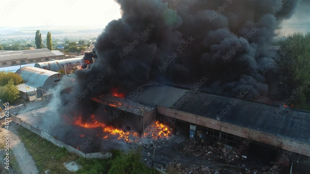 Severe fire in the warehouse. Black smoke in the sky. View from the drone over the fire Severe fire in the warehouse. Black smoke in the sky. View from the drone over the fire