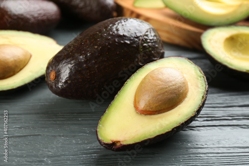Whole and cut avocados on grey wooden table, closeup