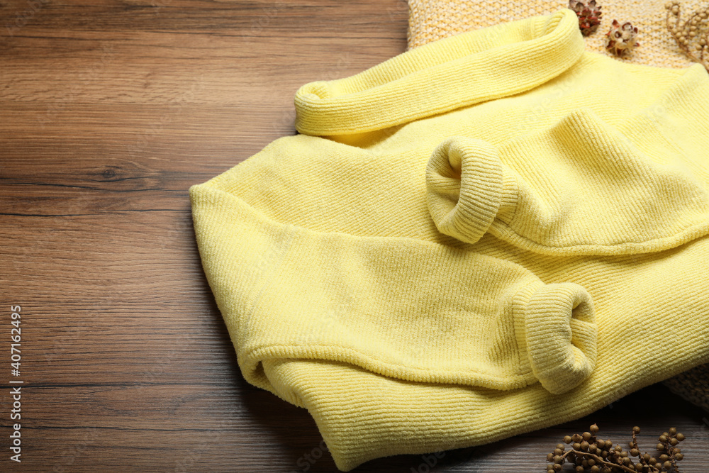 Yellow warm sweater with plaid on wooden table, closeup. Space for text Yellow warm sweater with plaid on wooden table, closeup. Space for text