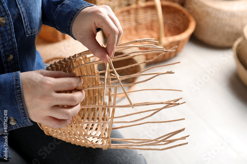 Obraz na plátně Woman weaving wicker basket indoors, closeup view