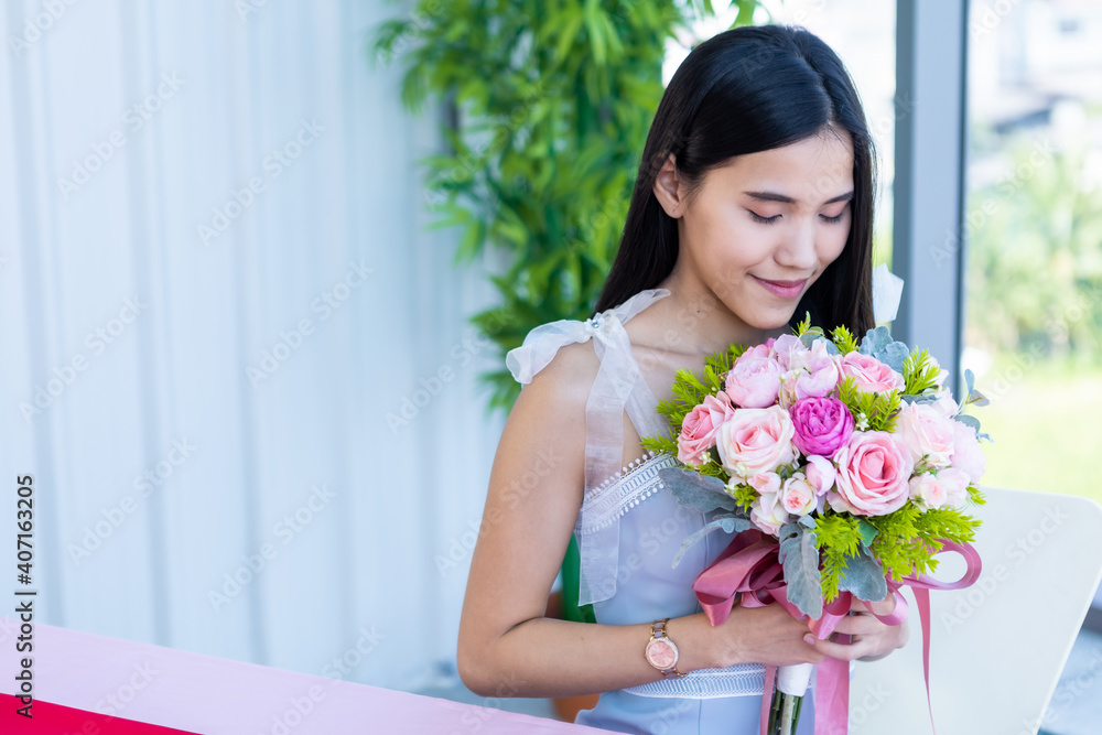 Valentine's day concept, Happy of smiling Asian young female sitting at a table food holding a bouquet of roses at in the restaurant background Valentine's day concept, Happy of smiling Asian young female sitting at a table food holding a bouquet of roses at in the restaurant background