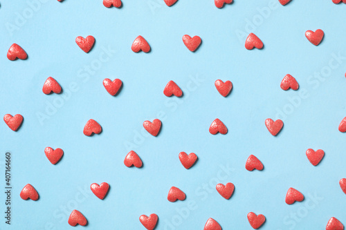 Pink heart shaped sprinkles on light blue background, flat lay