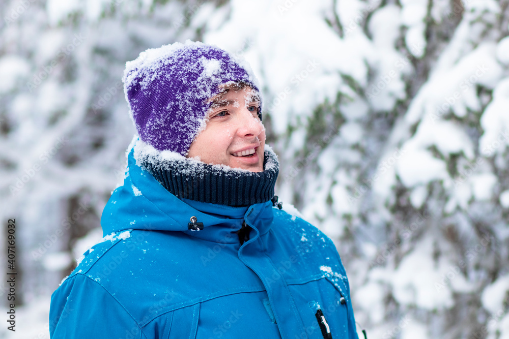Portrait of happy handsome guy in a winter snowy forest. Young man playing, enjoying walking outdoors in warm clothers in snow, smiling. Snowball game. Portrait of happy handsome guy in a winter snowy forest. Young man playing, enjoying walking outdoors in warm clothers in snow, smiling. Snowball game.