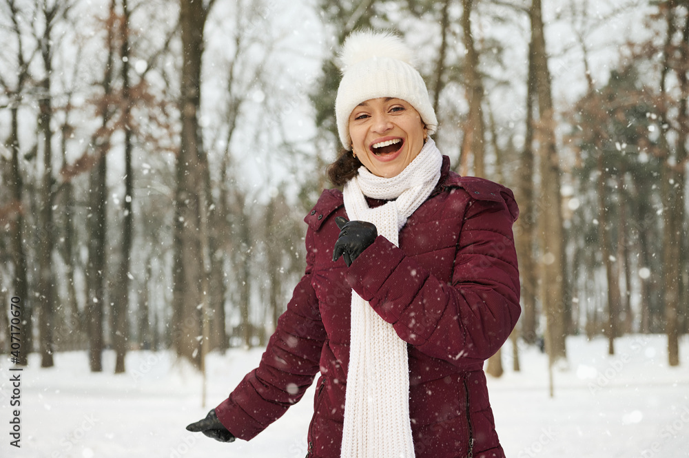 Outdoor photo of laughing woman in white knitted hat and scarf having fun in snowy morning on snowy winter forest. Outdoor photo of laughing woman in white knitted hat and scarf having fun in snowy morning on snowy winter forest.