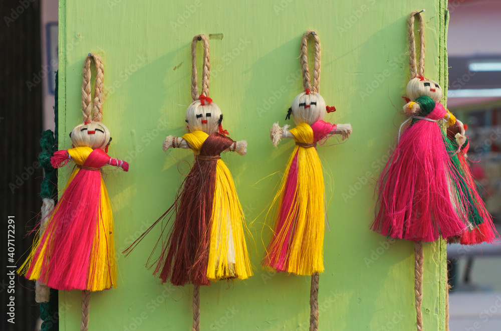 Vibrant multicolor jute dolls, used as wall hanging puppets in a retail display for sale at a handicraft fair in Kolkata.