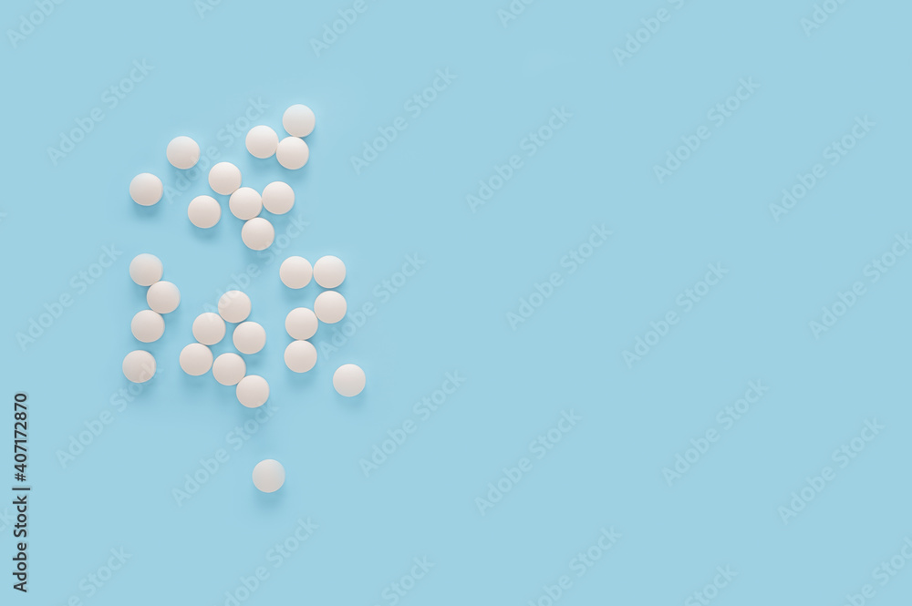white round pills, pills isolated on blue background. Scattered medicine pills. Healthcare, medical and pharmaceutical concept. copy space