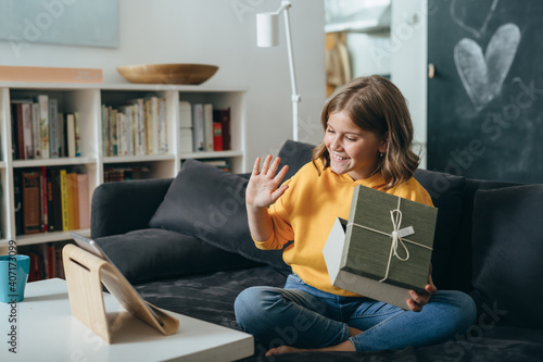 teenage girl sitting on sofa at home having video call