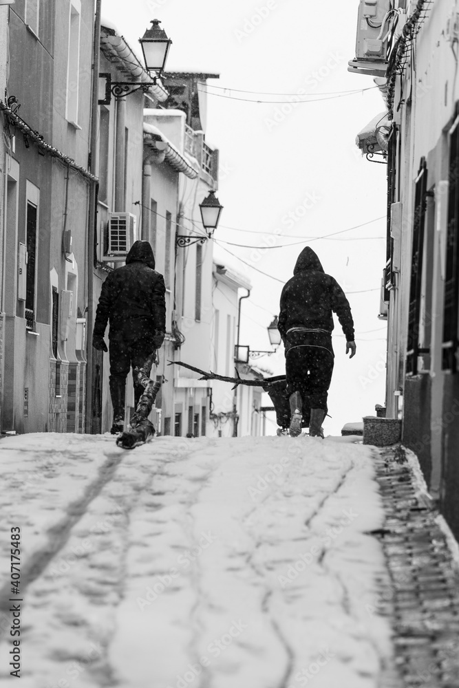 two people with wood on snowy street