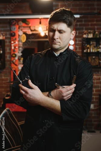 Portrait of handsome young man standing at barber shop. Stylish hairstylist standing in his salon with his arms crossed.