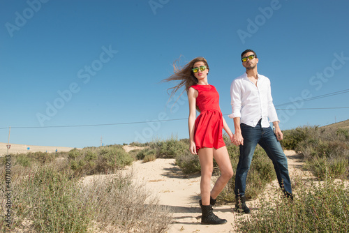young couple wearing sunglasses enjoying the beach and stroll