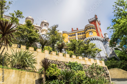 View of the clock tower, wall and palm trees in the Pena National Palace in Sintra town, Portugal