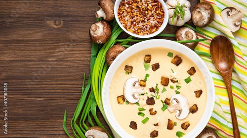 Delicious cream soup, made of mushrooms with croutons on a wooden background. Top view. Copy space.