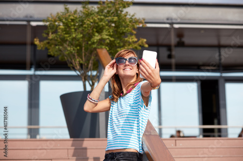 Young woman using modern smartphone outdoors.