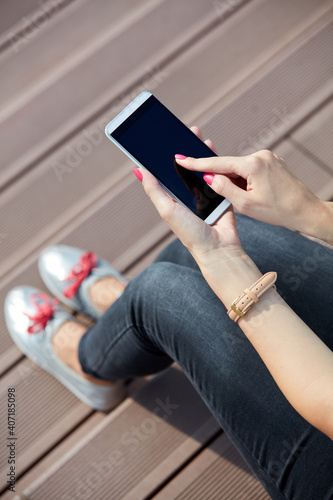 Young woman using modern smartphone outdoors. photo