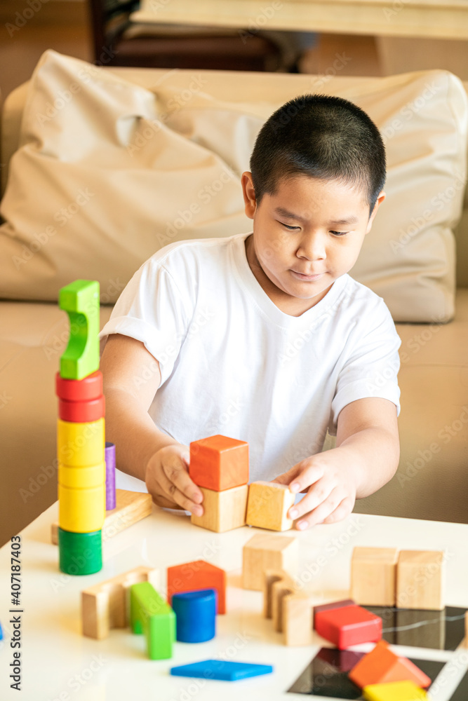 Asian boy playing wooden block a creative toy in a living room at home. Asian kids concept Asian boy playing wooden block a creative toy in a living room at home. Asian kids concept