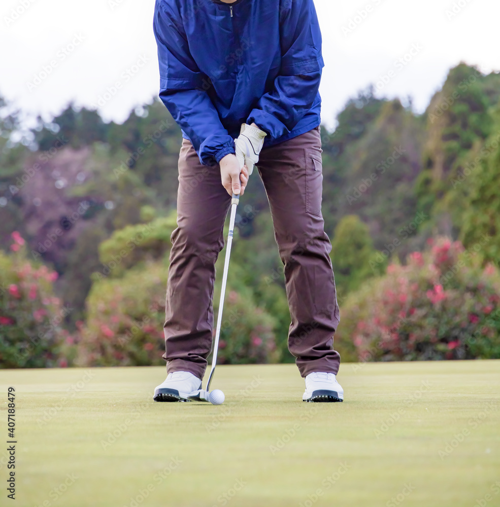 Obraz premium ゴルフ場でパターのショットをする男性