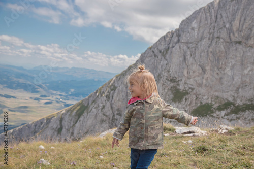 Little girl running, enjoying freedom and have fun in mountains.