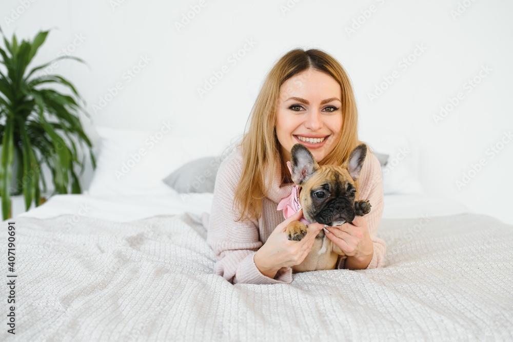 Obraz premium Young woman playing with her dog at home