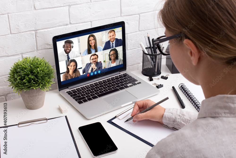 Female Taking Notes Sitting At Laptop Having Video Call Indoors Female Taking Notes Sitting At Laptop Having Video Call Indoors