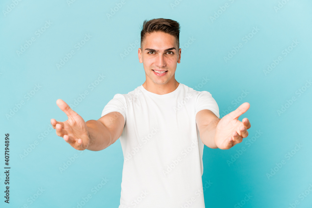 Young caucasian handsome man isolated showing a welcome expression.