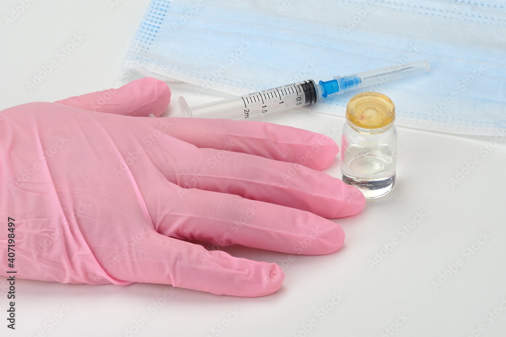 A doctor in medical gloves holds a syringe and a